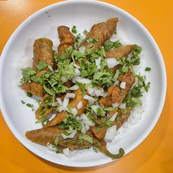 Cumin N Eat's chili pakora, deep-fried peppers topped with fresh cilantro and diced onions.